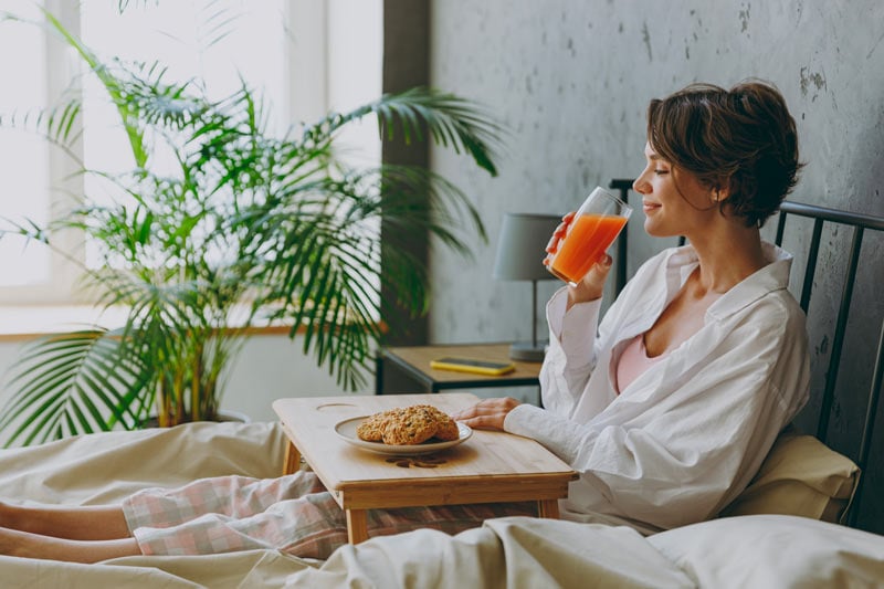 woman drinking ornage juice in bed